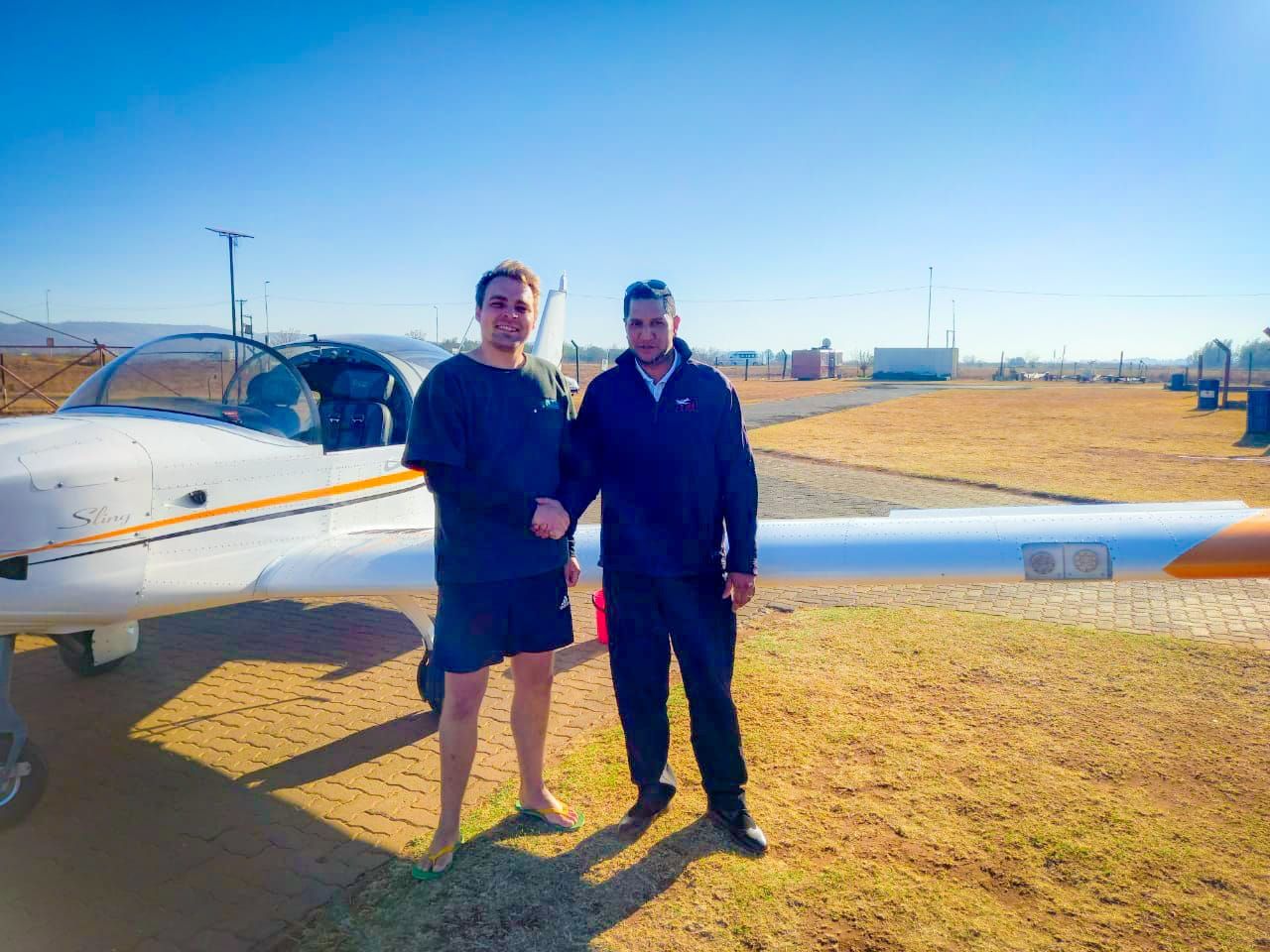 A student and instructor shaking hands in front of a JFA Sling at Panorama Airfield